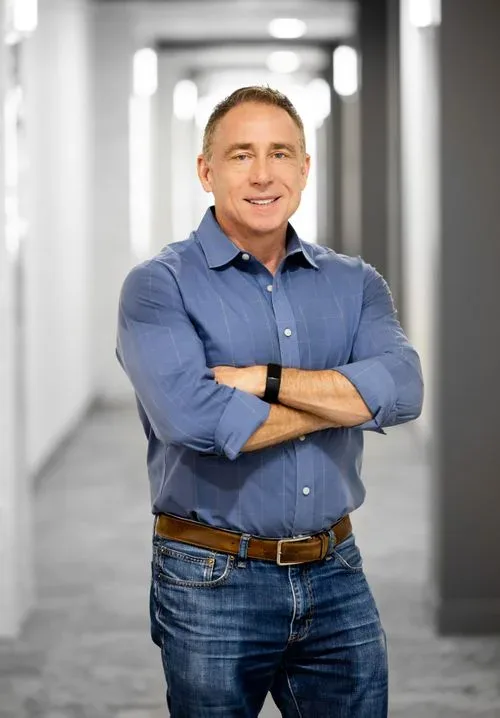 A man in a blue shirt standing in a hallway.