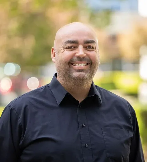 A bald man smiling in a black shirt.